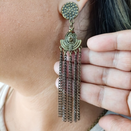 Brinco longo estilo boho com corrente ouro velho e base redonda texturizada, em orelha feminina.