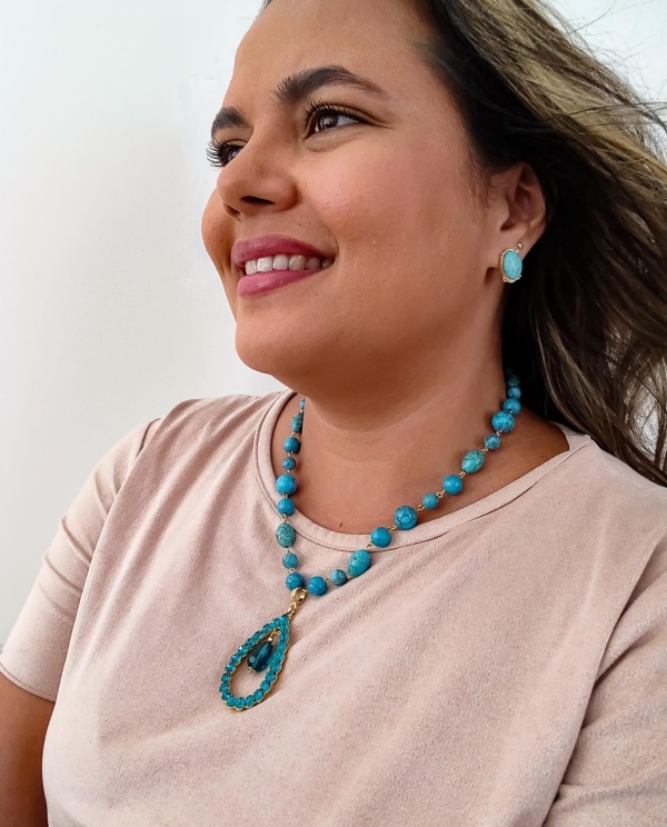 Colar boho azul com pedras turquesa e pingente em forma de gota, usado por mulher sorridente.