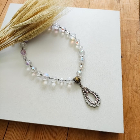 Colar boho com cristais em tons de âmbar e caramelo, com pingente vintage oval e fundo branco decorado com ramo de trigo.