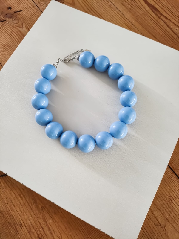 Colar artesanal de esferas grandes azul brilhante com fecho metálico ajustável.