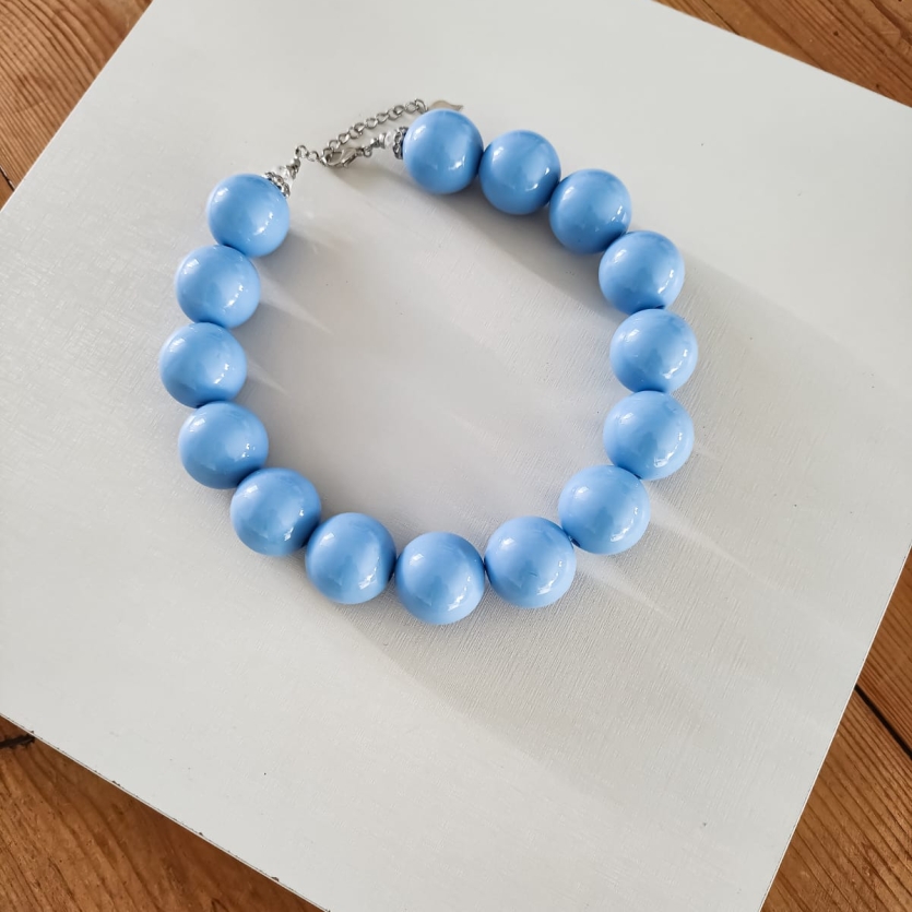 Colar artesanal de esferas grandes azul brilhante com fecho metálico ajustável.