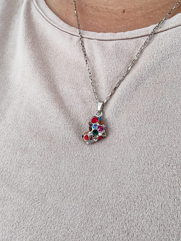 Colar com pingente de coração cravejado de strass multicoloridos em corrente prata.