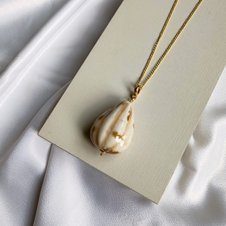Colar longo dourado com pingente em formato de gota bege com detalhes marmorizados.